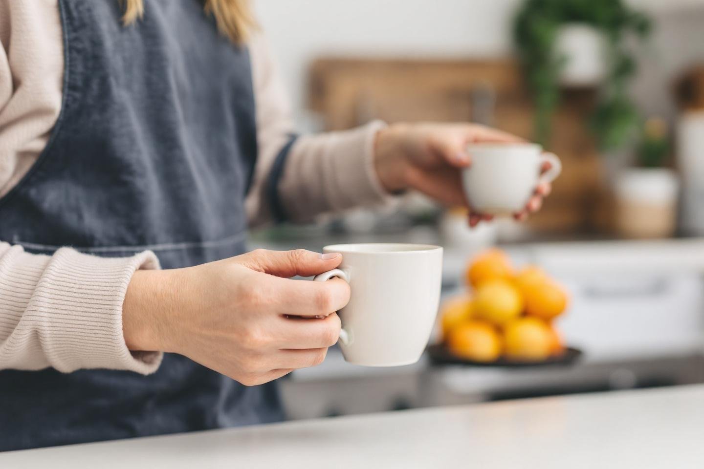 Main tenant une tasse blanche avec des citrons en arrière-plan